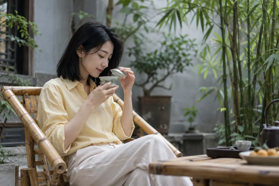 竹影院落中，竹椅与盖碗茶摆放在石桌旁